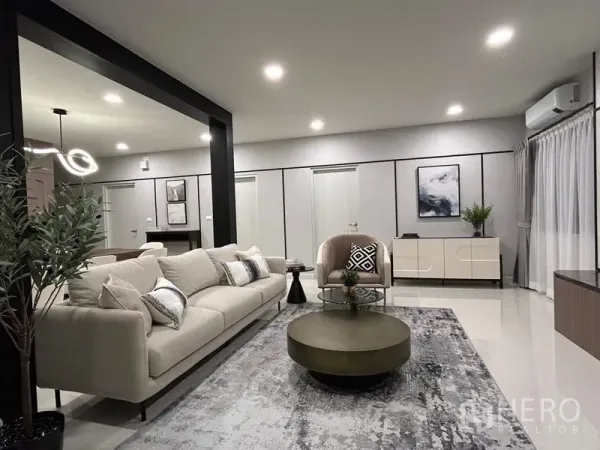 Detached House for rent or sale in Bang Phli, Samut Prakan - Contemporary living room with cream sofa, round coffee table, recessed lighting and a black feature frame.