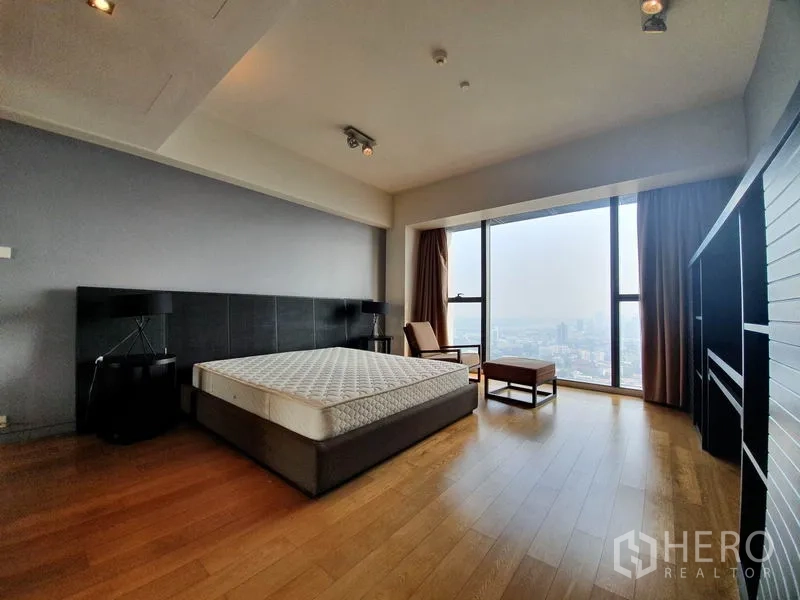 公寓 出租在Sathon, Bangkok - 宽敞主卧，木地板与躺椅，落地窗城市景。