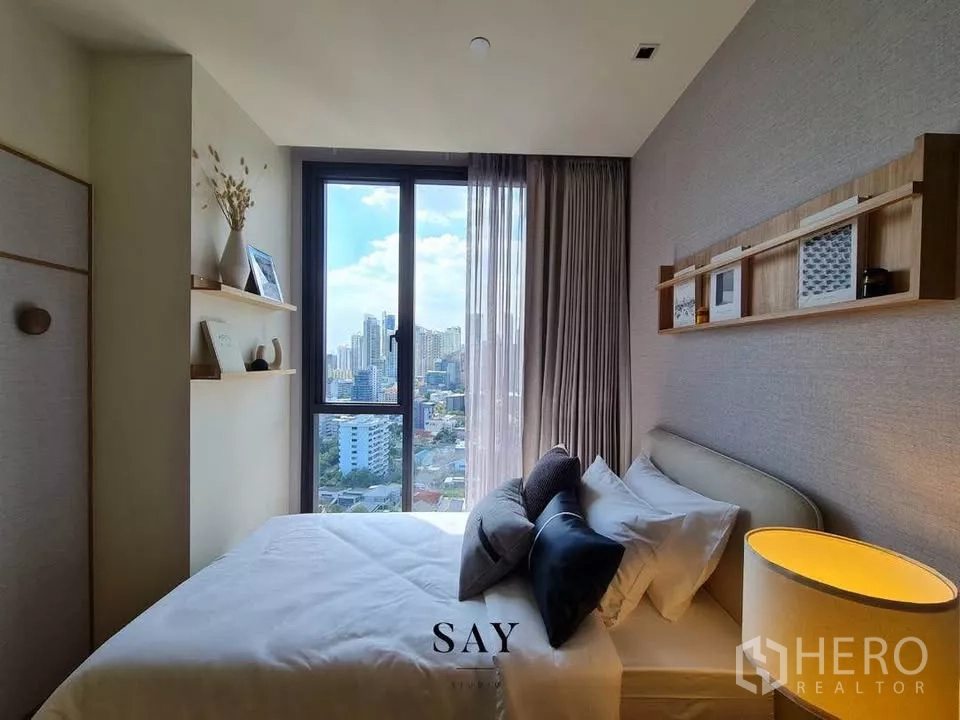 公寓 出租或出售在Khlong Toei, Bangkok - 次卧带大窗，床边壁架与城市景观。