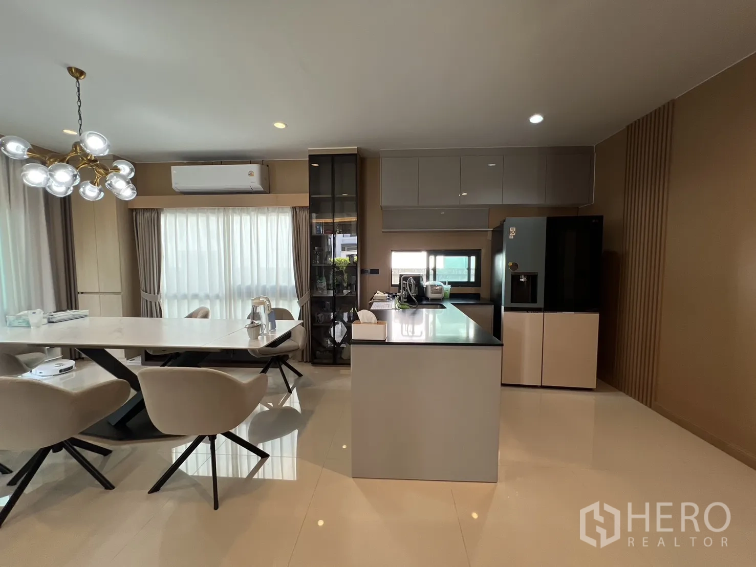 Detached House for rent or sale in Mueang Pathum Thani, Pathum Thani - Modern open kitchen with island, glossy counters and tall windows.