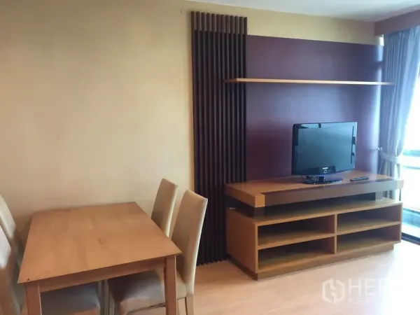 Condominium for rent in Sathon, Bangkok - Dining table next to TV console with floating shelf and slatted feature wall.