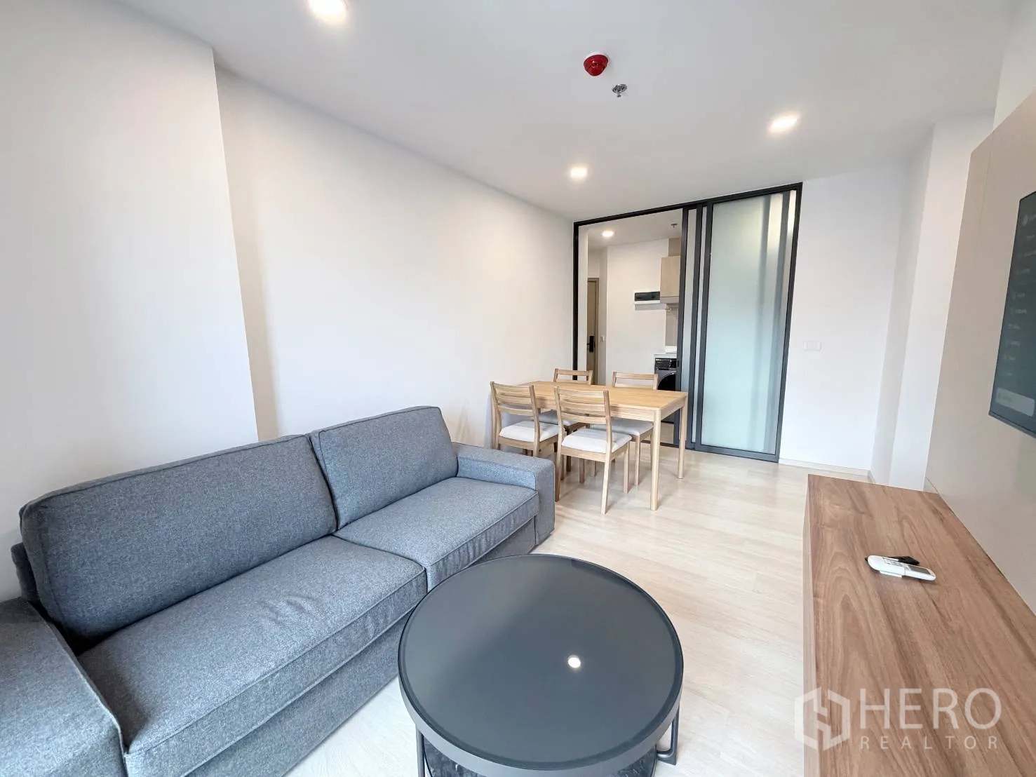 คอนโด for rent in Din Daeng, Bangkok - พื้นที่นั่งเล่นแบบเปิดโล่งกับโซฟา โต๊ะกลาง และชุดโต๊ะอาหาร ถัดจากทางเข้าครัว
