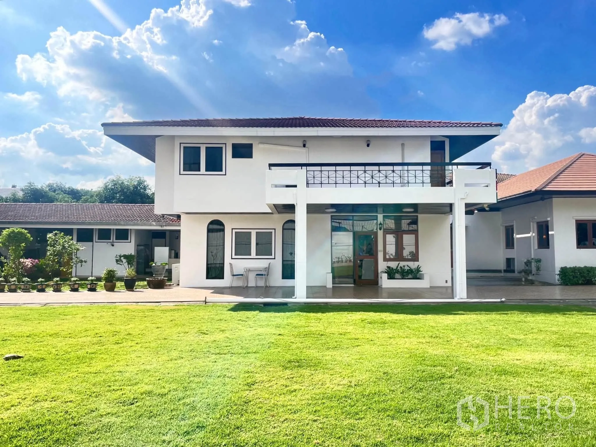Home Office for rent in Bang Na, Bangkok - Two-storey white house with balcony opening onto a wide green lawn.