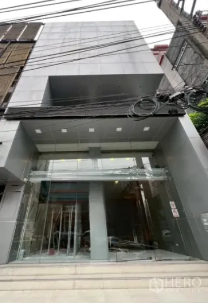 Retail Space for rent in Watthana, Bangkok - Modern retail building facade with full-height glass entrance and clean grey cladding.