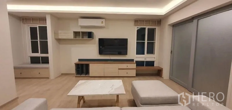 Detached House for rent - Living room with sofa set, wall-mounted TV, and sliding glass doors.