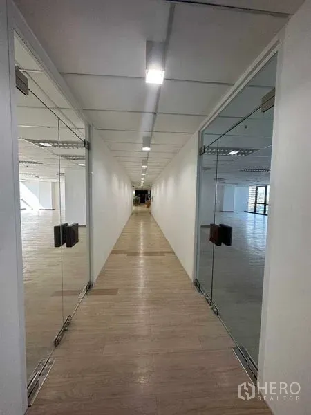 สำนักงาน ให้เช่าในWatthana, Bangkok - โถงทางเดินสว่างพร้อมประตูกระจกคู่ พื้นลายไม้ และไฟฝ้าฝังเพดานนำสู่ห้องสำนักงาน