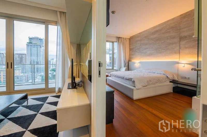 Condominium for rent in Pathum Wan, Bangkok - View from hallway showing living room and bedroom divided by a sliding door, both opening to a balcony with skyline views.