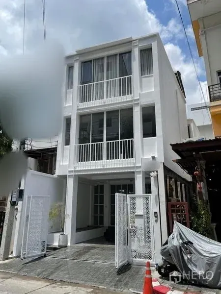 Townhouse for sale in Din Daeng, Bangkok - Front approach to a bright three-storey townhouse with sliding gate and paved forecourt.