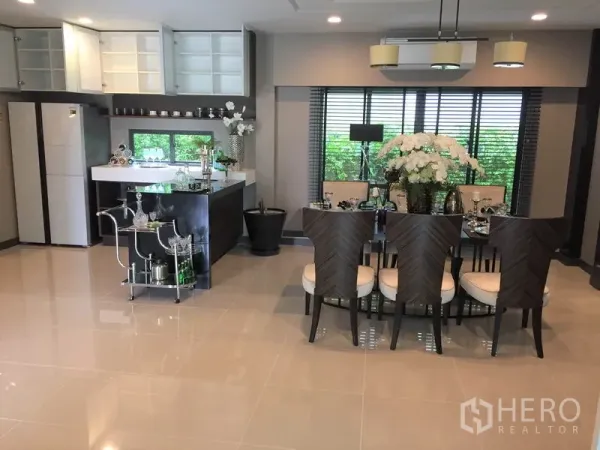 Detached House for rent or sale in Bang Kapi, Bangkok - Open-plan dining area with six-seat table beside pantry and upper cabinets.