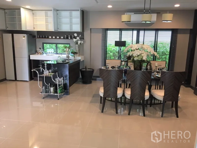 Detached House for rent or sale in Bang Kapi, Bangkok - Open-plan dining area with six-seat table beside pantry and upper cabinets.
