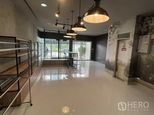 Detached House for rent or sale in Don Mueang, Bangkok - Ground‑floor showroom with glossy tiles, pendant lights and shelving units.