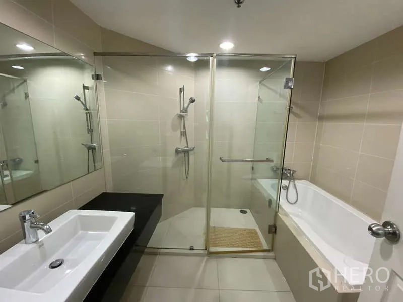 Condominium for  in Huai Khwang, Bangkok - Bathroom with separate glass shower and bathtub plus long mirror and rectangular basin.
