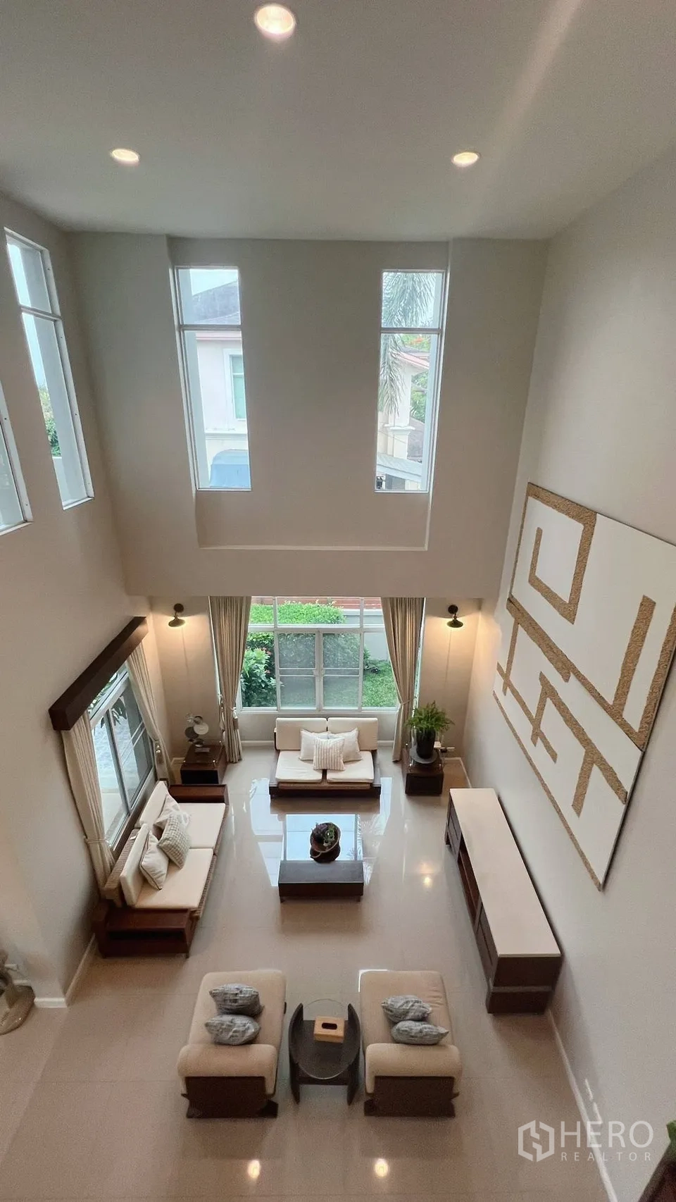 Detached House for rent in Lat Krabang, Bangkok - Double-height living room viewed from upstairs with tall windows and sofas.