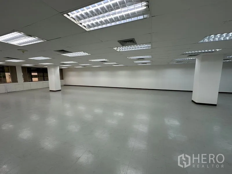 สำนักงาน ให้เช่าในWatthana, Bangkok - พื้นสำนักงานขนาดใหญ่โล่ง ๆ เพดานแบบกริดไฟสว่าง ผนังสีขาว พื้นไวนิลสีเทา และเสาโครงสร้าง.
