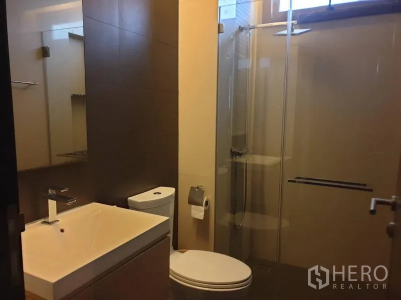 Detached House for sale in Watthana, Bangkok - Modern bathroom with glass shower enclosure, vanity and toilet.