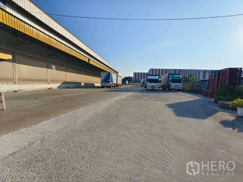 คลังสินค้า ให้เช่าในSamut Prakan - ลานคอนกรีตกว้างข้างโกดัง มีรถบรรทุกจอดสำหรับขนถ่ายสินค้า