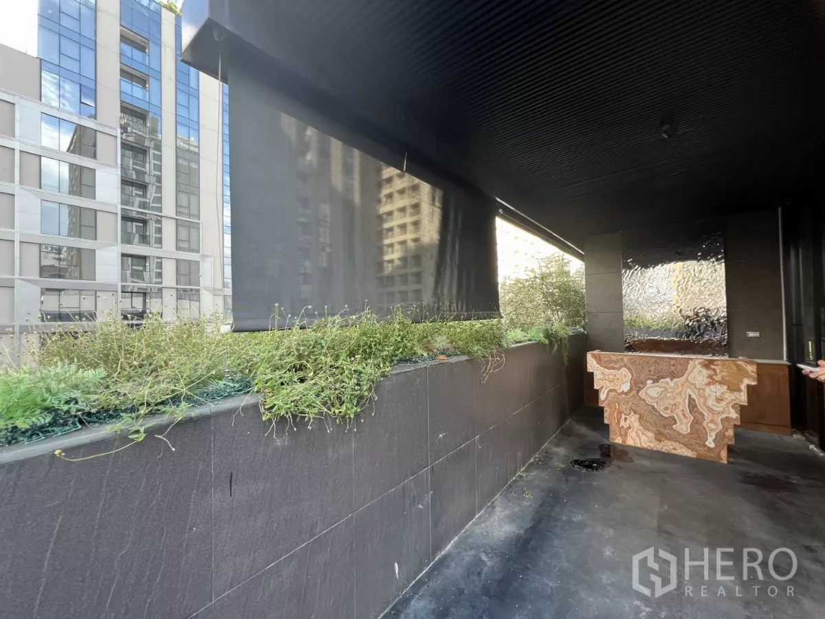 Retail Space for rent - Shaded outdoor walkway with planters and nearby city buildings.