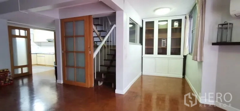 Townhouse for rent in Watthana, Bangkok - Open-plan living and dining area with leather sofa set, pendant lights and wood floors