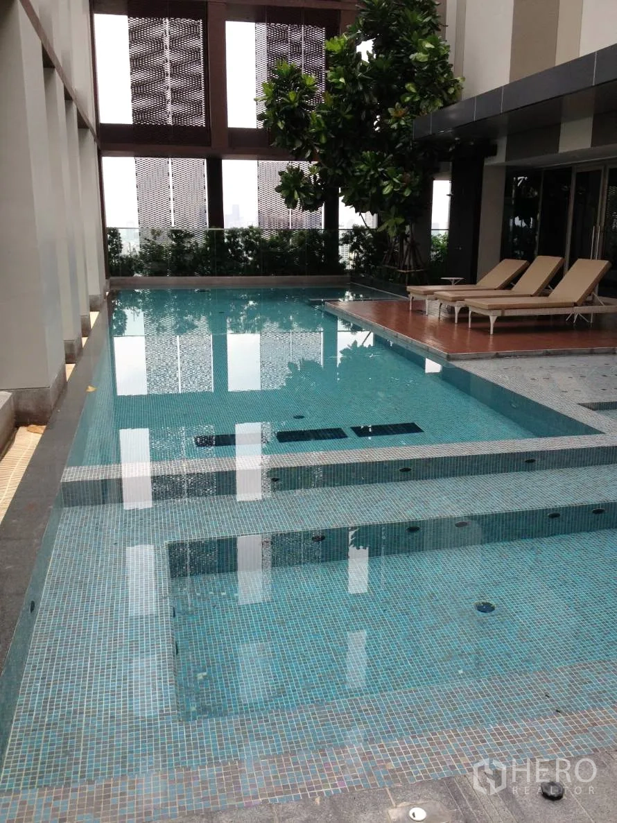 Condominium for rent in Khlong Toei, Bangkok - Condominium swimming pool with mosaic tiles, sundeck and sun loungers.
