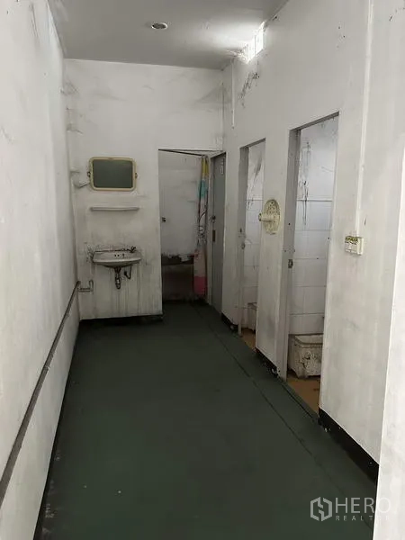 工厂 出租在Bang Bua Thong, Nonthaburi - 厂内卫生间走廊，含洗手盆与隔间门。