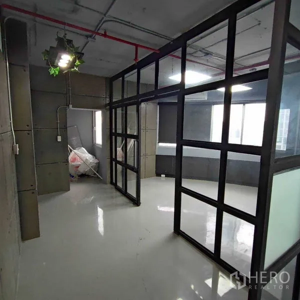 办公空间 出租在Watthana, Bangkok - 玻璃会议室旁走廊通向储物区，工业质感明显。