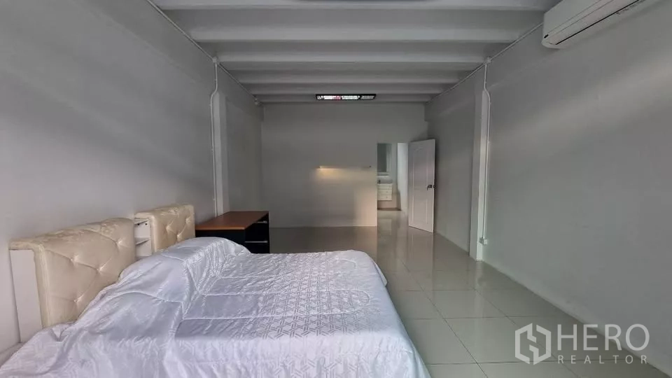 ทาวน์เฮาส์ ให้เช่าในHuai Khwang, Bangkok - ห้องนอนกว้าง มีเตียง โต๊ะ พื้นกระเบื้อง และเครื่องปรับอากาศ