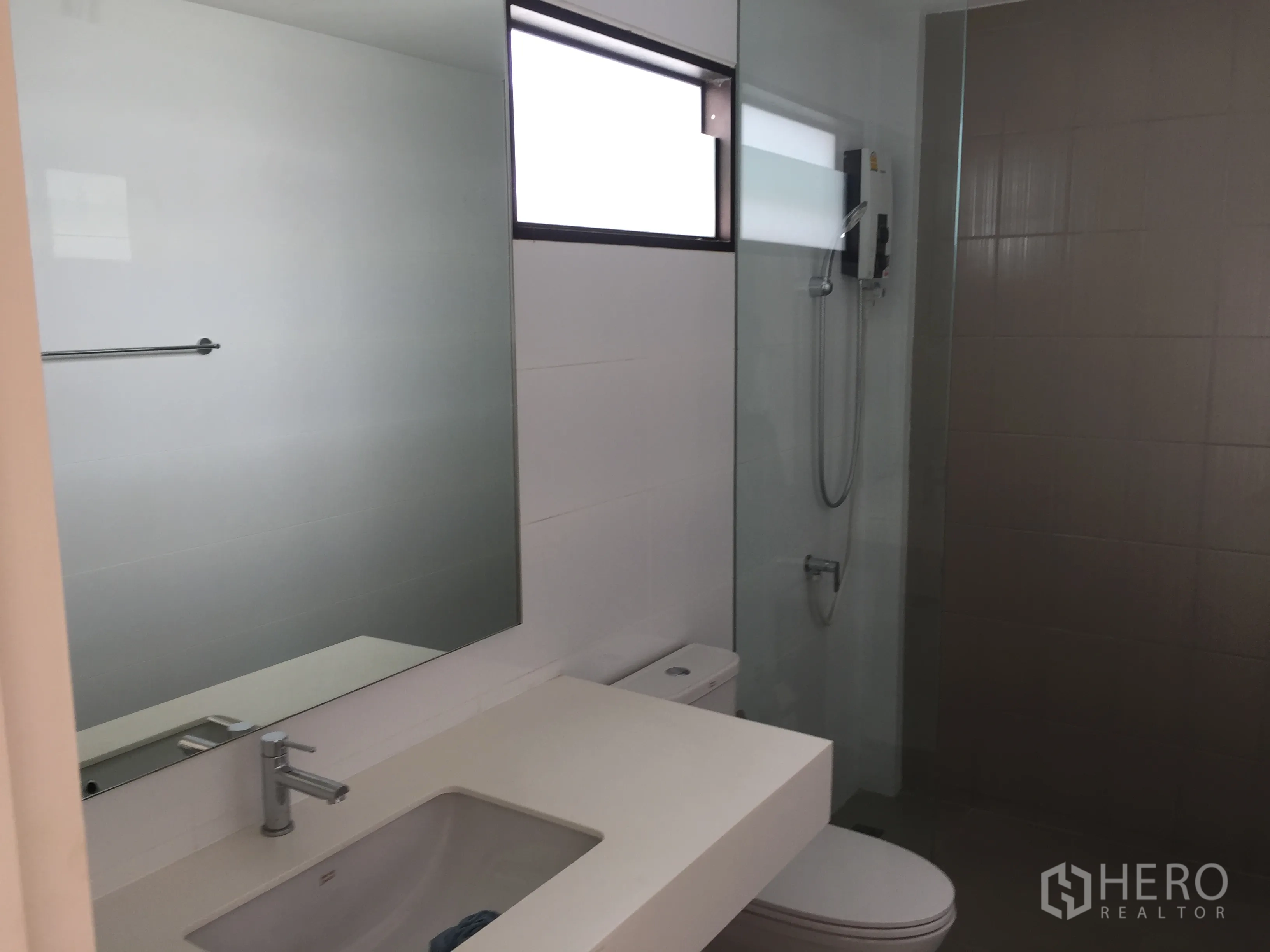 Townhouse for rent in Saphan Sung, Bangkok - Contemporary bathroom with large mirror, vanity, toilet and glass-enclosed shower.