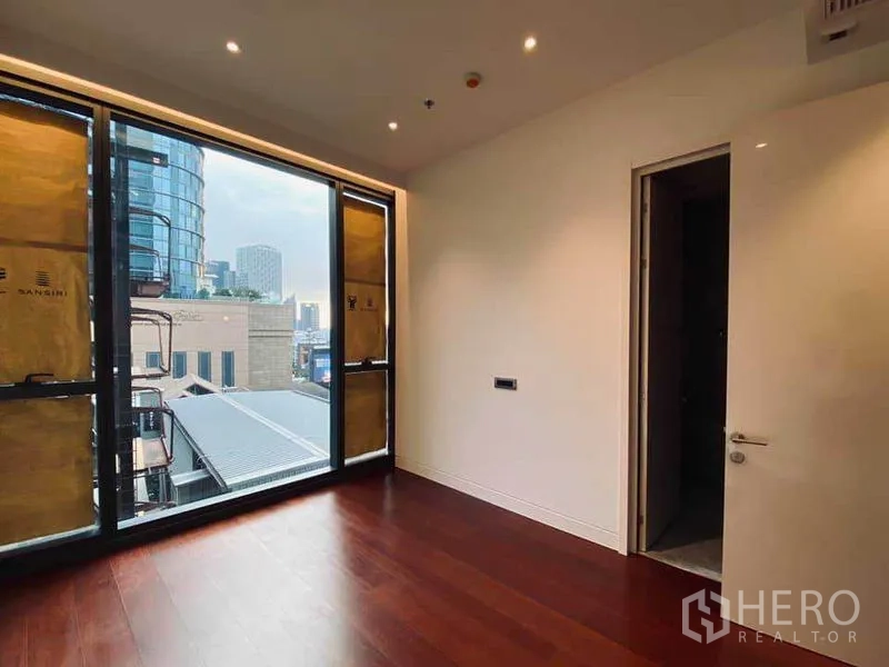 Condominium for sale in Watthana, Bangkok - Bedroom with large window, city outlook, recessed lighting, and wood flooring.