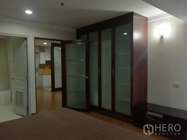 公寓 出租在Khlong Toei, Bangkok - 卧室配大面积玻璃衣柜，可见厨房与浴室入口。