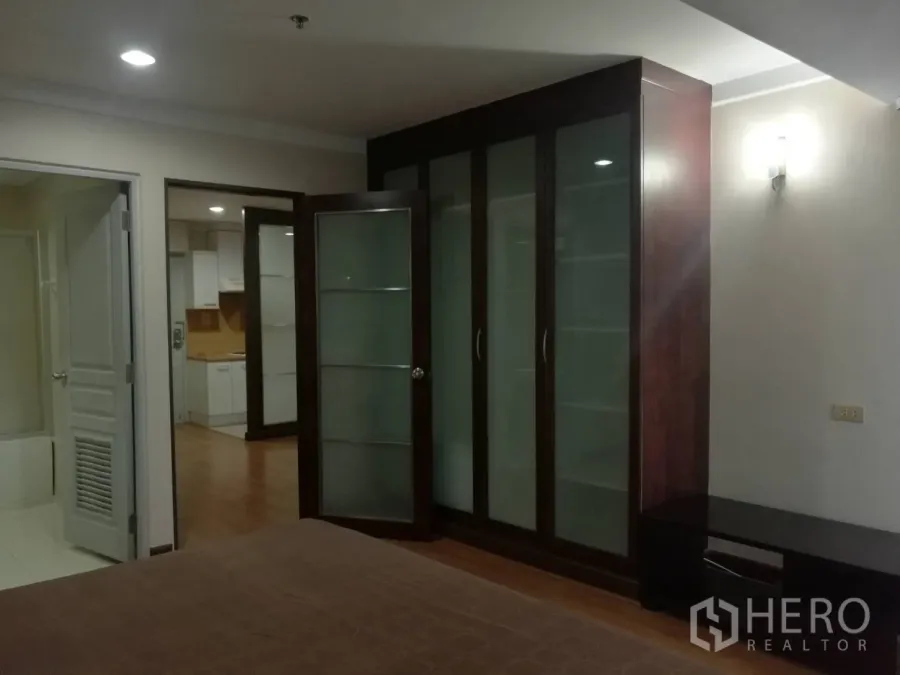公寓 出租在Khlong Toei, Bangkok - 卧室配大面积玻璃衣柜，可见厨房与浴室入口。