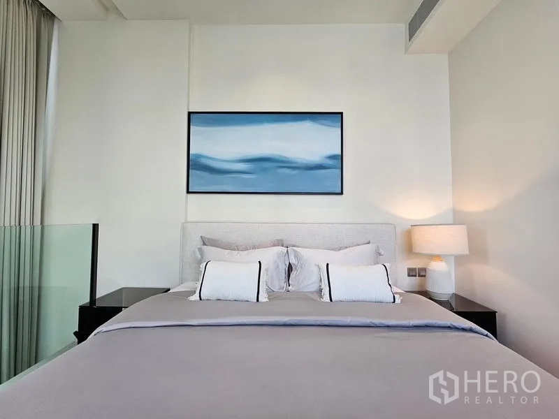 Condominium for rent - Cozy bedroom with upholstered bed, bedside lamps, and abstract artwork above the headboard.