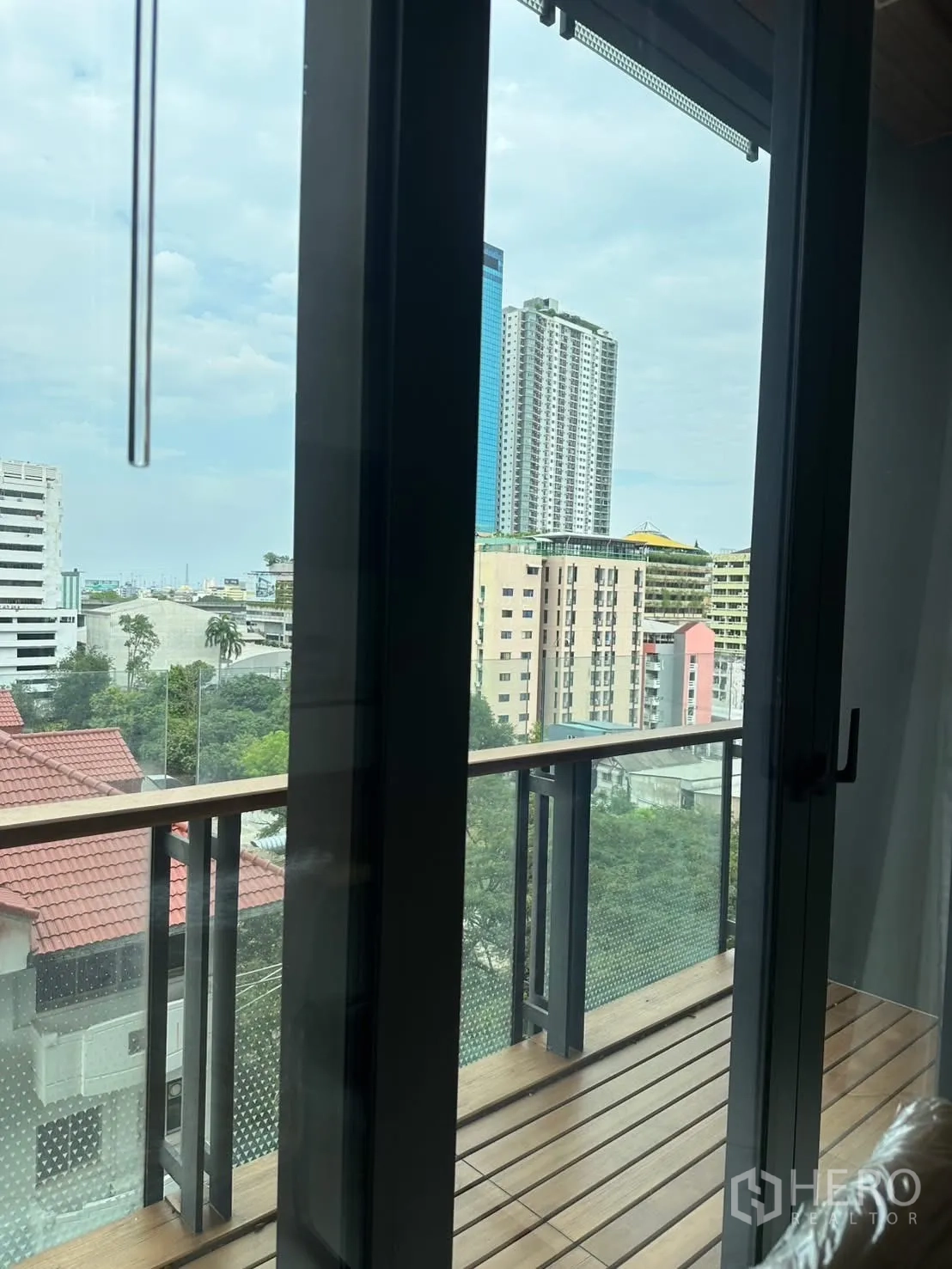 Condominium for rent or sale in Watthana, Bangkok - Balcony doors opening to a city view over low-rise roofs and towers.