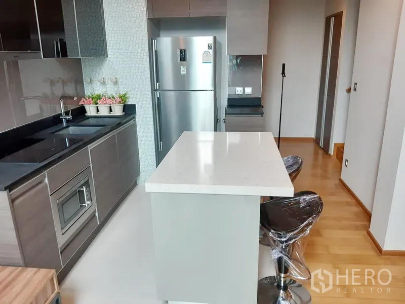 คอนโด ให้เช่าในKhlong Toei, Bangkok - ครัวโทนเทาเรียบหรู ตู้บิลท์อิน ผนังกระเบื้องโมเสก ตู้เย็นสแตนเลส และไอแลนด์พร้อมสตูลบาร์