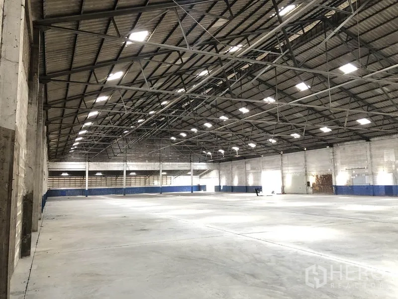 货栈 出租在Pak Kret, Nonthaburi - 斜角视图展示宽阔仓库，平整地面与清晰的大跨度钢屋顶。