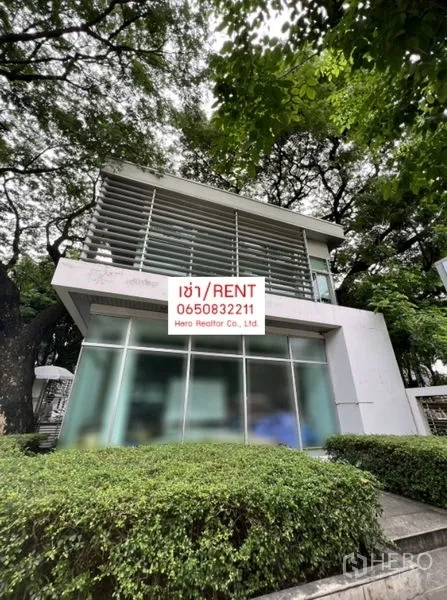 Office Space for rent in Khlong Toei, Bangkok - Angle view of a white contemporary two‑storey office building with large glass walls and manicured hedges under leafy shade.