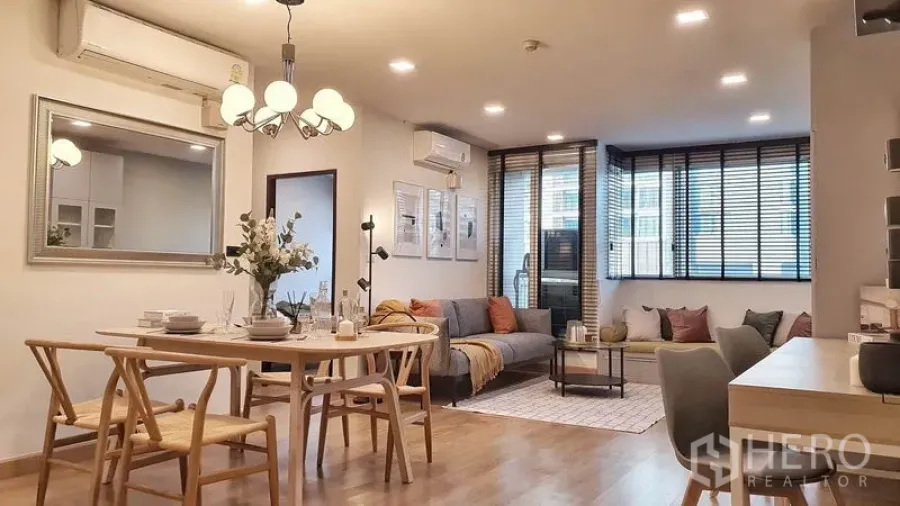 公寓 出租在Khlong Toei, Bangkok - 采光充足的客餐厅一体空间，木地板、吊灯、大窗配百叶与舒适沙发角落。