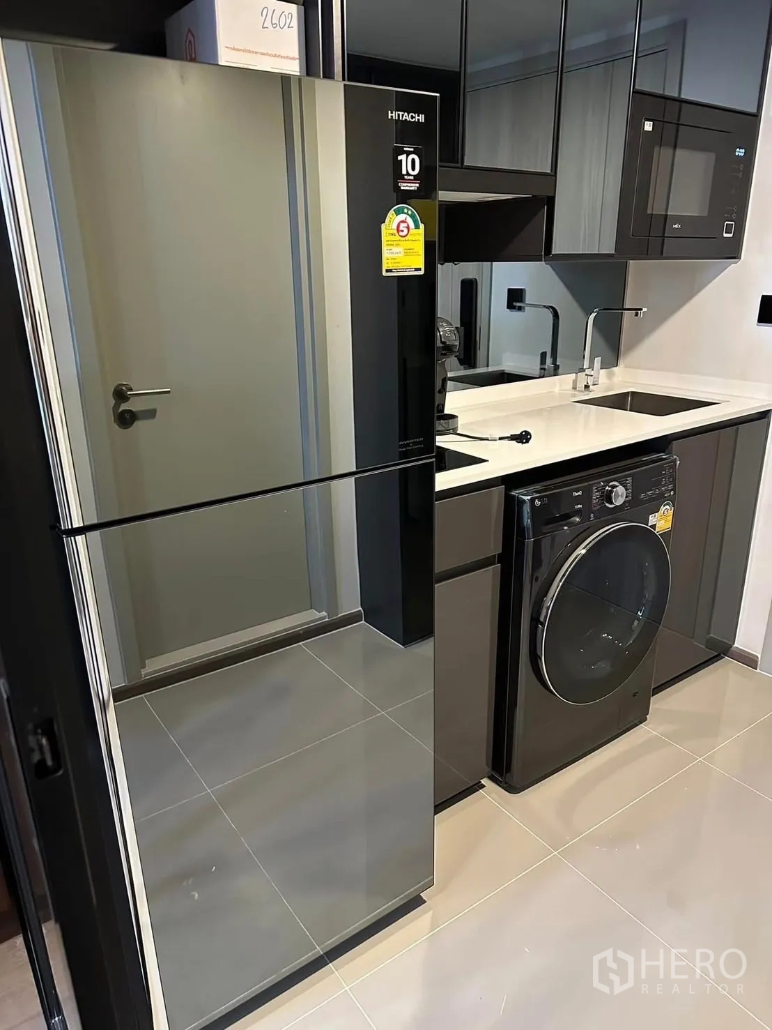 公寓 出租在Bang Rak, Bangkok - 现代紧凑厨房，配镜面冰箱、洗烘一体机、微波炉与水槽。