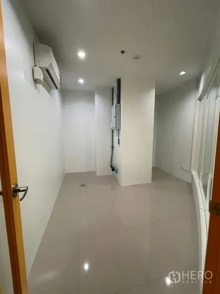 Office Space for rent in Khlong Toei, Bangkok - Compact office room with tiled floor, recessed lighting, wall-mounted air conditioner and a utility panel.