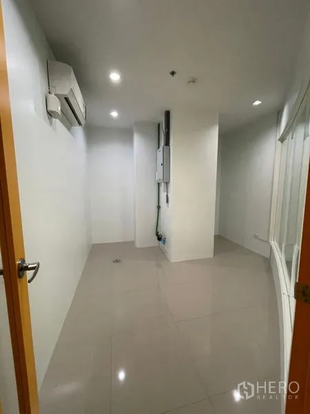 Office Space for rent in Khlong Toei, Bangkok - Compact office room with tiled floor, recessed lighting, wall-mounted air conditioner and a utility panel.