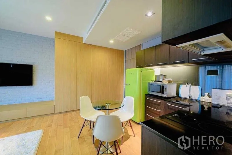 Condominium for rent in Watthana, Bangkok - Compact kitchen with dark cabinets, round dining table and retro green refrigerator.