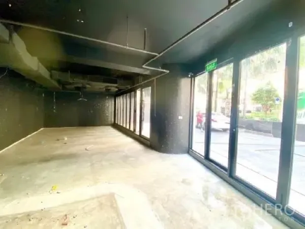 零售空间 出租在Khlong Toei, Bangkok - 空置零售内部，高挑空间，外露管线，混凝土地面与面街落地窗。