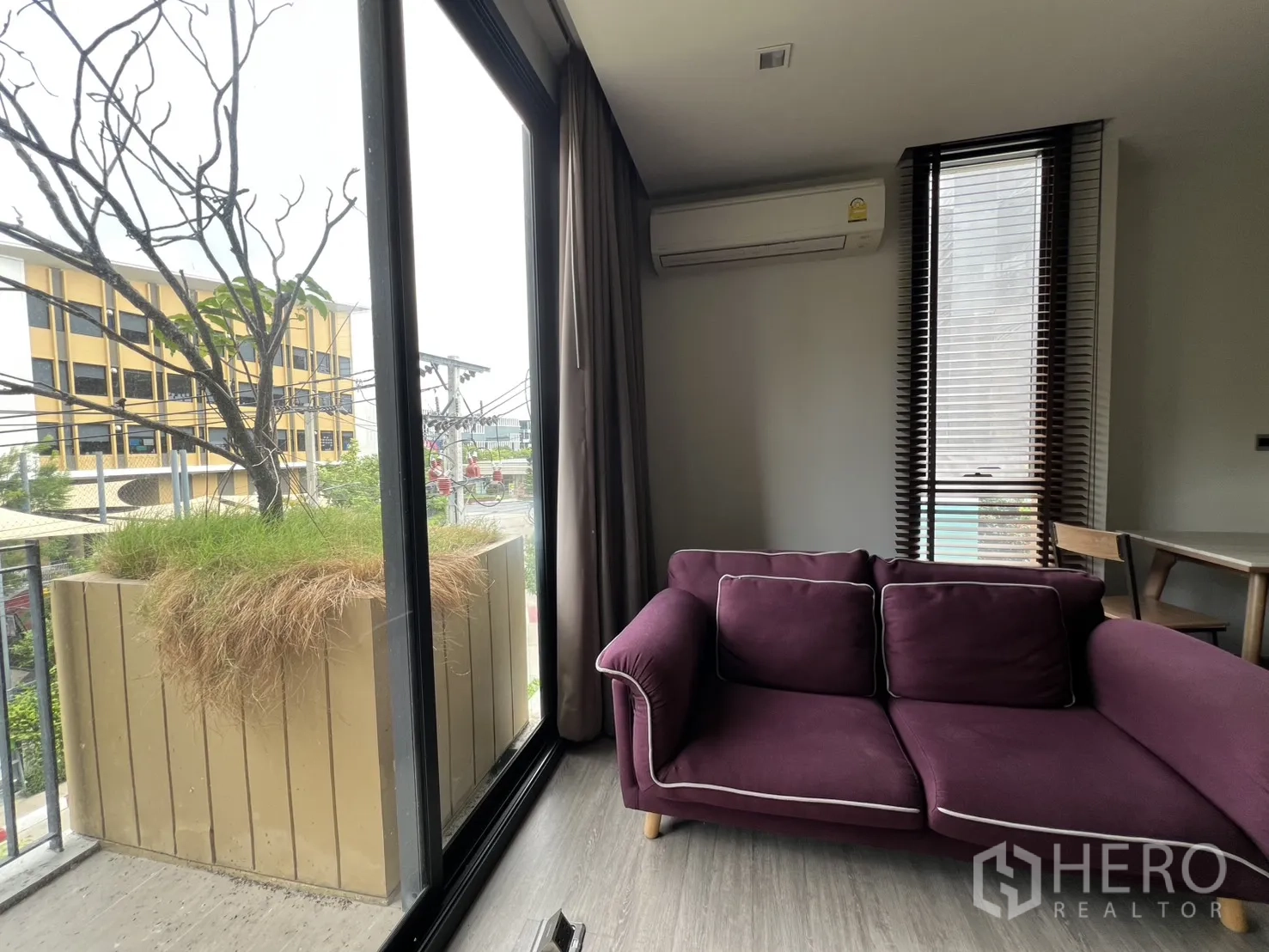 Condominium for rent in Watthana, Bangkok - Living room corner with large sliding doors and a purple sofa beside the window.