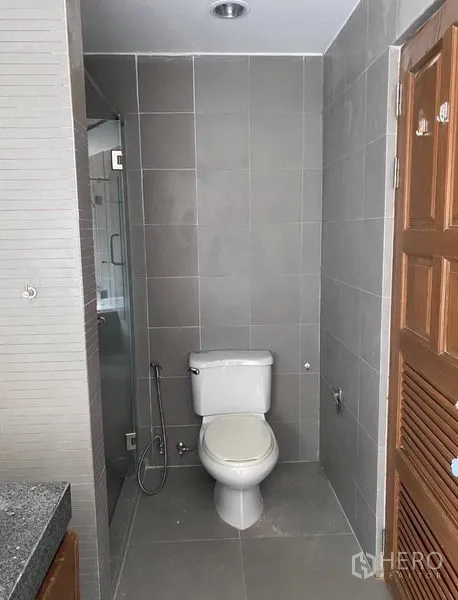 คอนโด ให้เช่าในWatthana, Bangkok - โซนสุขภัณฑ์ปูกระเบื้องสีเทา พร้อมสายชำระ และห้องอาบน้ำกระจกข้างเคียง