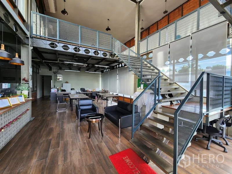 Home Office for rent in Mueang Nonthaburi, Nonthaburi - Reception and coworking zone with mezzanine stair, sofas and wood-look flooring.
