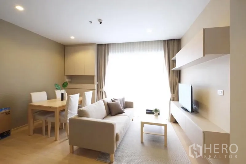 公寓 出租在Watthana, Bangkok - 开放式客餐厅，沙发、电视墙与四人餐桌