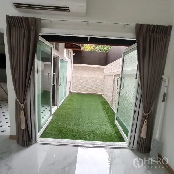 Townhouse for rent in Wang Thonglang, Bangkok - Private courtyard with artificial grass bordered by sliding glass doors.