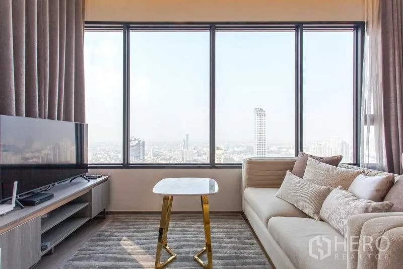 Condominium for rent in Watthana, Bangkok - Sofa and TV beside a full-width window with a small marble table and panoramic city view.
