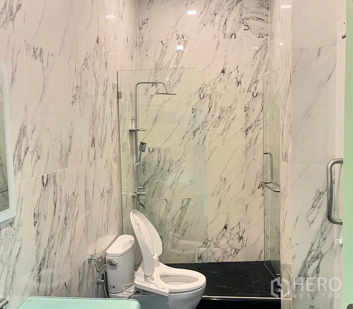 Shophouse for rent in Bang Rak, Bangkok - Marble-tiled bathroom with toilet and walk-in shower with glass divider.