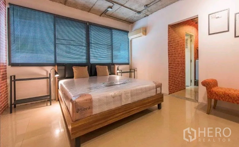 Condominium for rent in Watthana, Bangkok - Primary bedroom with large windows, blinds and access to an en-suite bathroom.