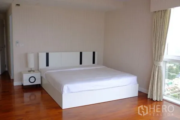 公寓 出租在Watthana, Bangkok - 明亮主卧，白色平台床、木地板，落地窗享曼谷城市景观。